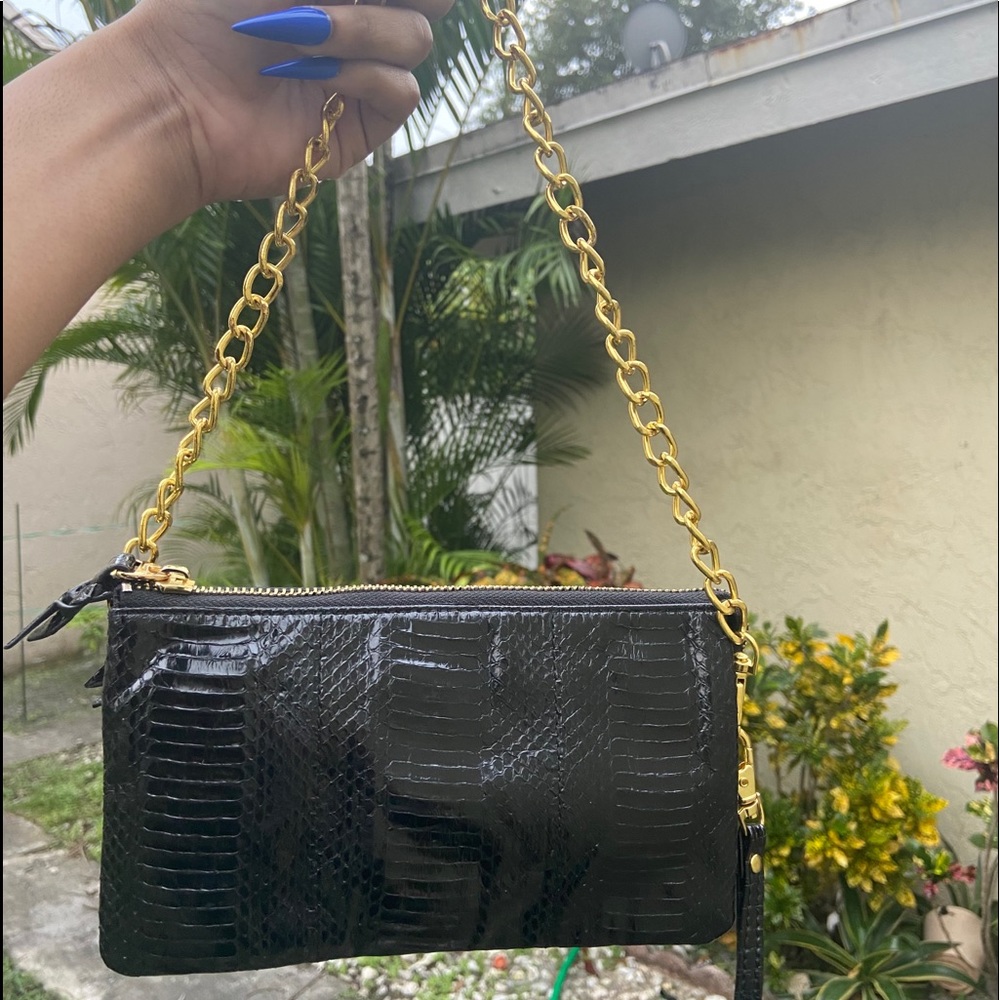 Black snakeskin wristlet with golden handle.